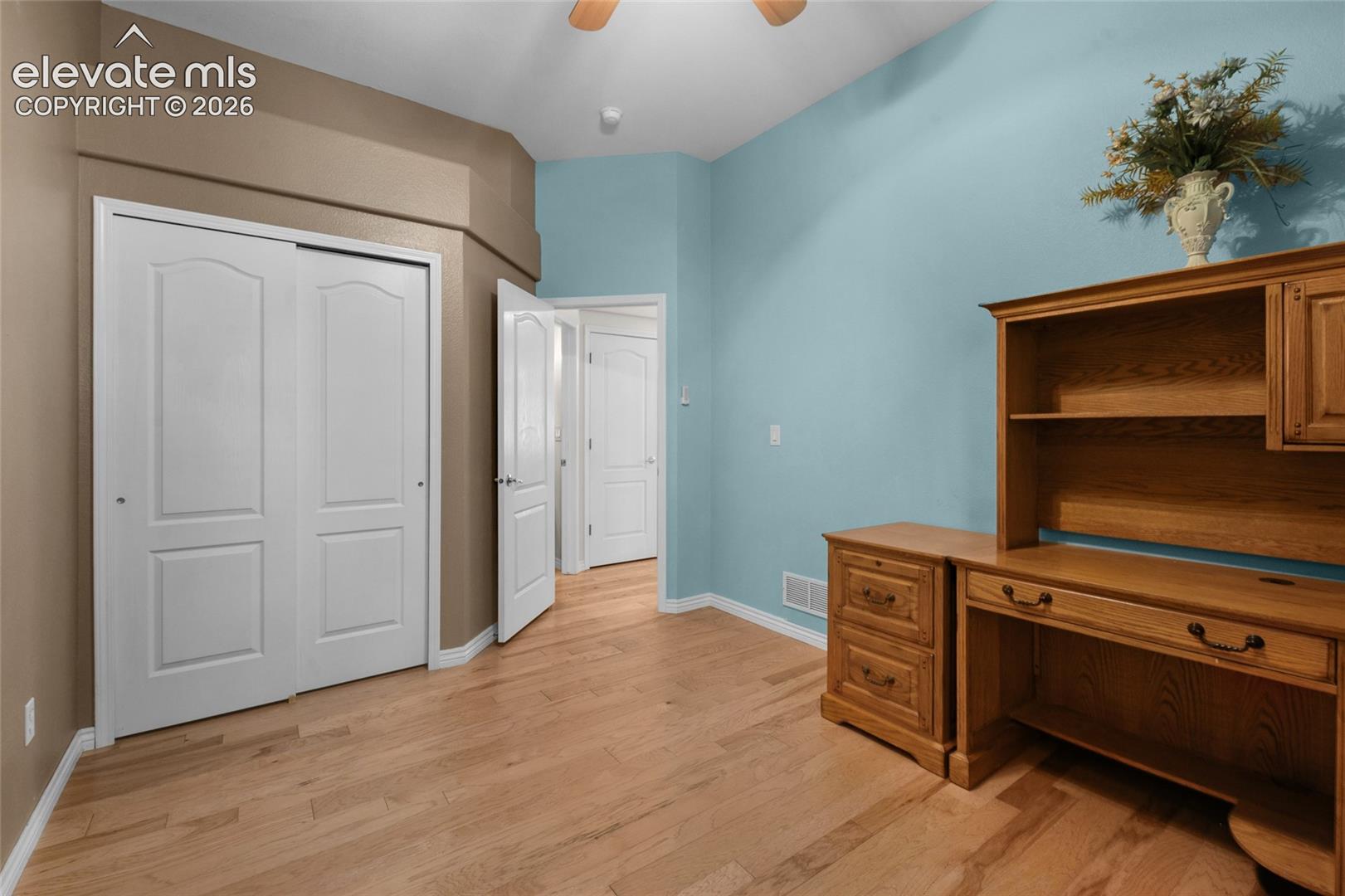 Interior space featuring wood-finish flooring, vaulted ceilings, and a sliding-door closet with paneled detail