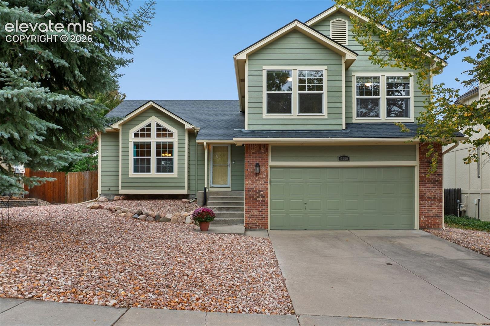 Two-story exterior with light green siding and brick accents