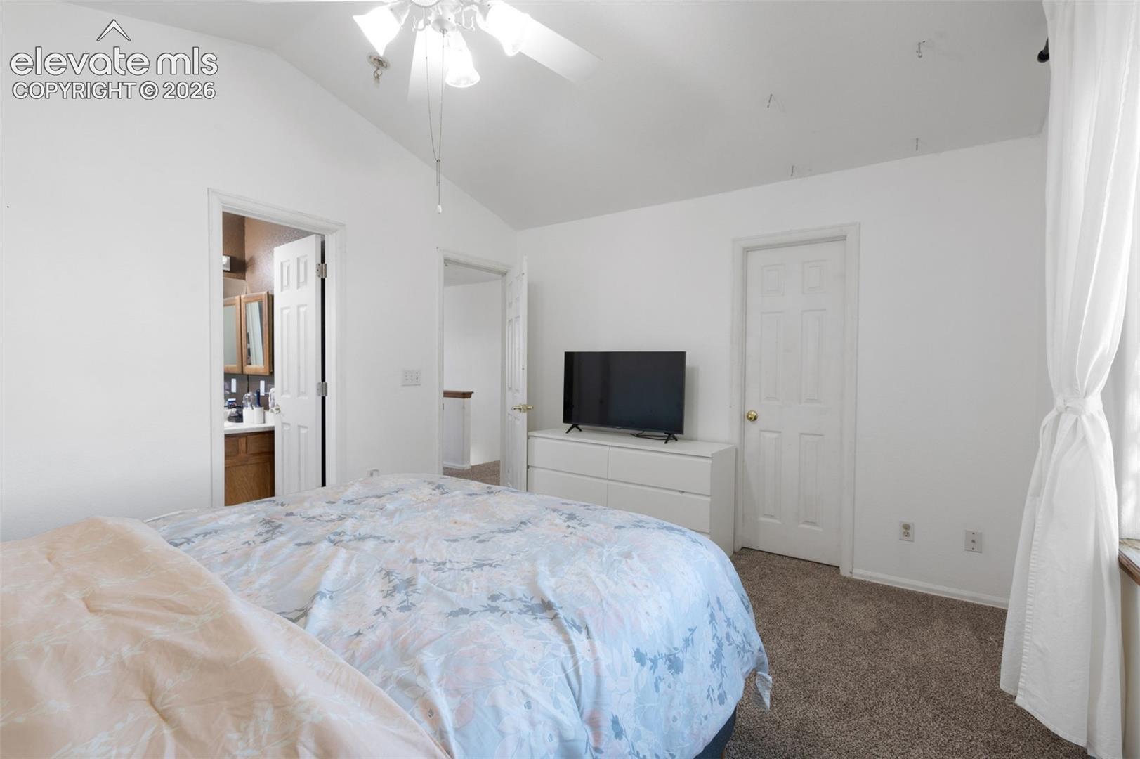 Bedroom featuring vaulted ceilings, ceiling fan, neutral wall paint, and carpet flooring