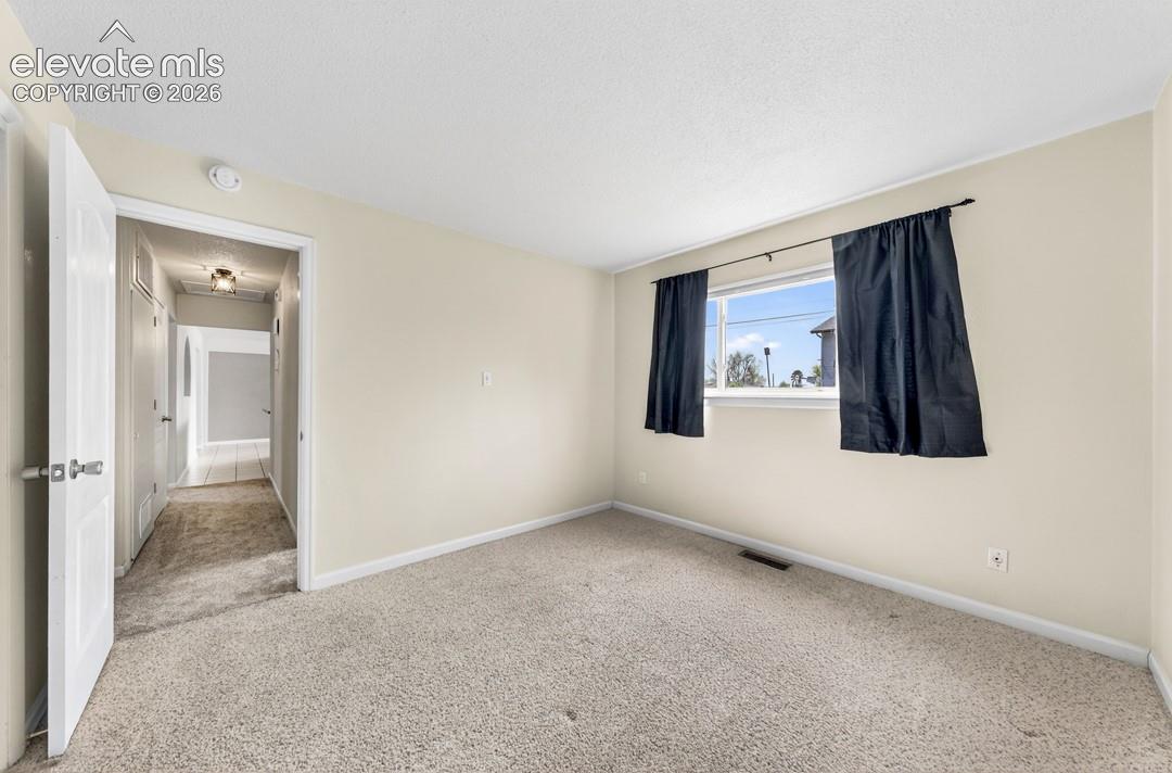 Neutral wall paint, carpeted flooring, and a window with a curtain rod