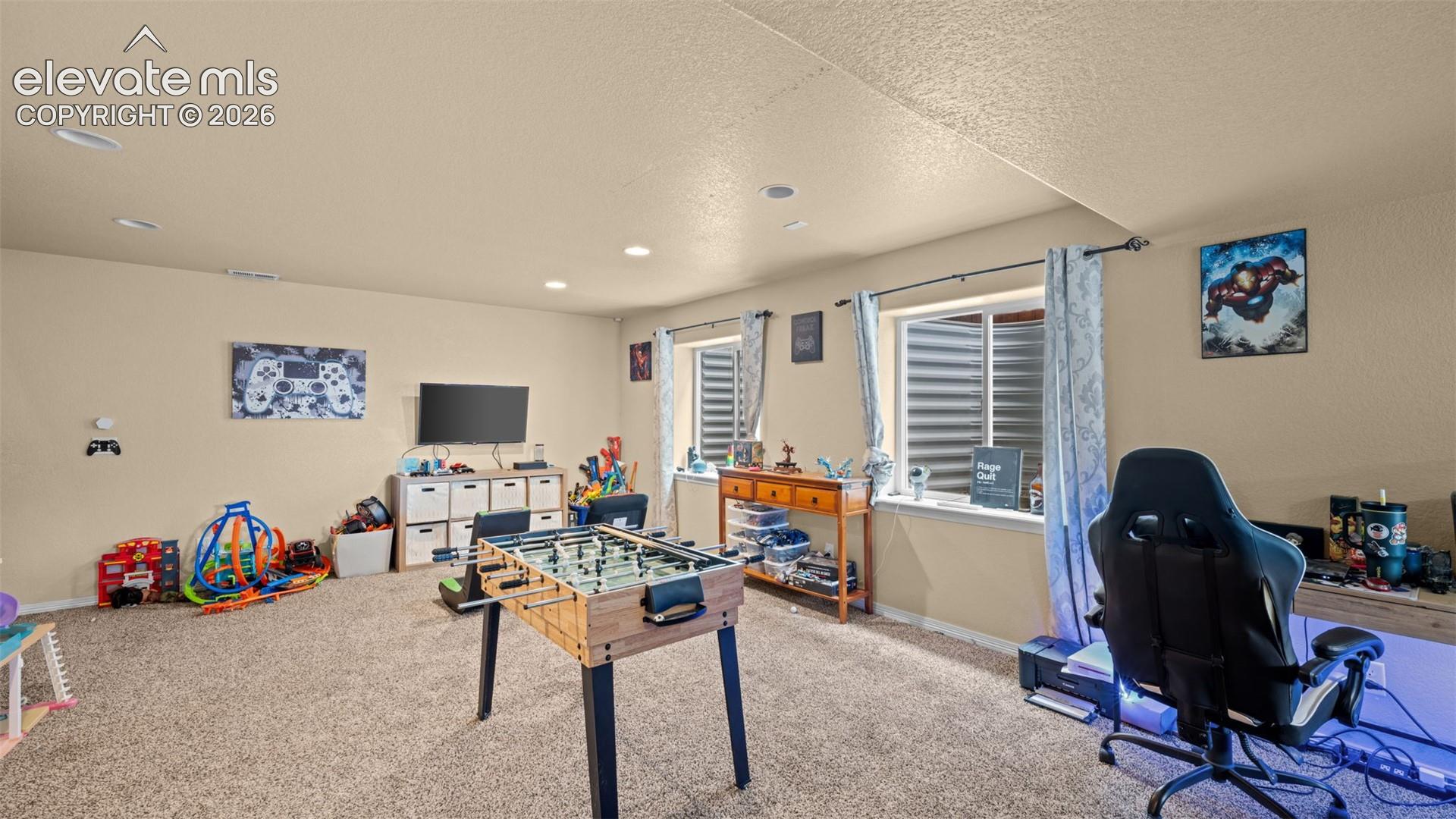 Spacious carpeted room featuring recessed lighting, multiple windows with blinds, and neutral wall tones