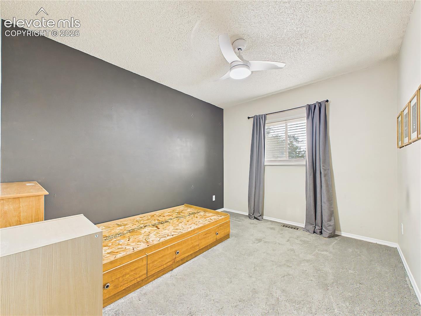 Comfortable secondary bedroom with neutral finishes, an accent wall, and flexible space for a variety of furniture arrangements.