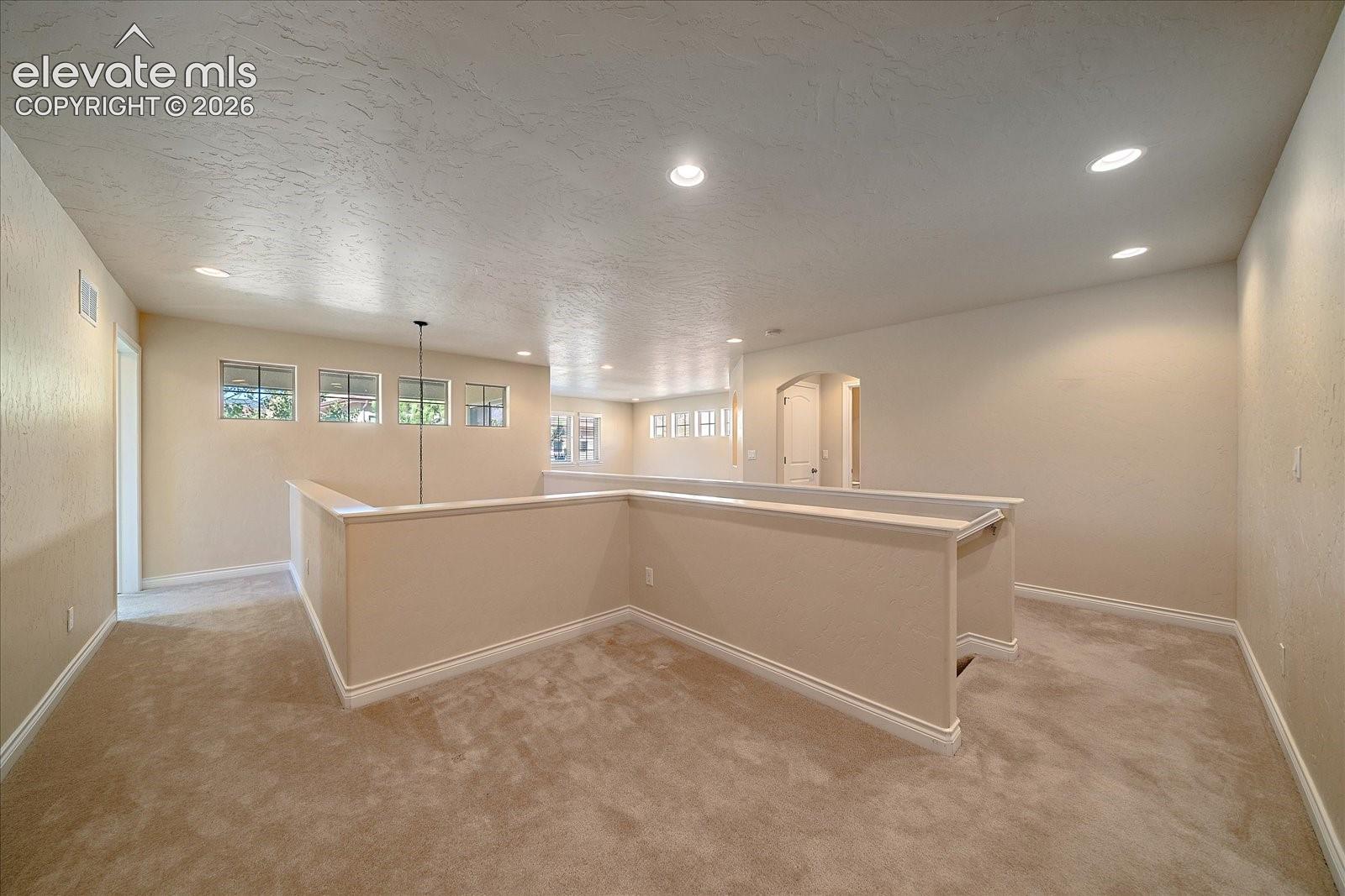 Open floor plan featuring recessed lighting, carpeted flooring, neutral wall tones, and multiple windows
