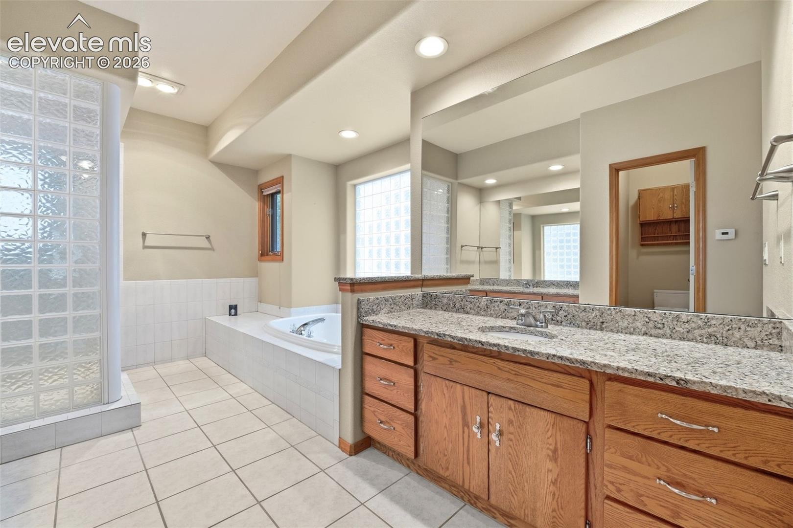 Bathroom featuring a large vanity with a granite countertop, dual sinks, and wood cabinetry