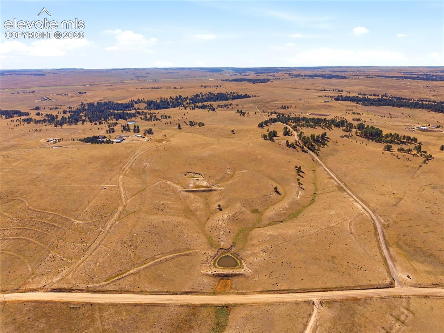 Expansive acreage featuring rolling topography, natural terrain, a dedicated pond, and direct road access