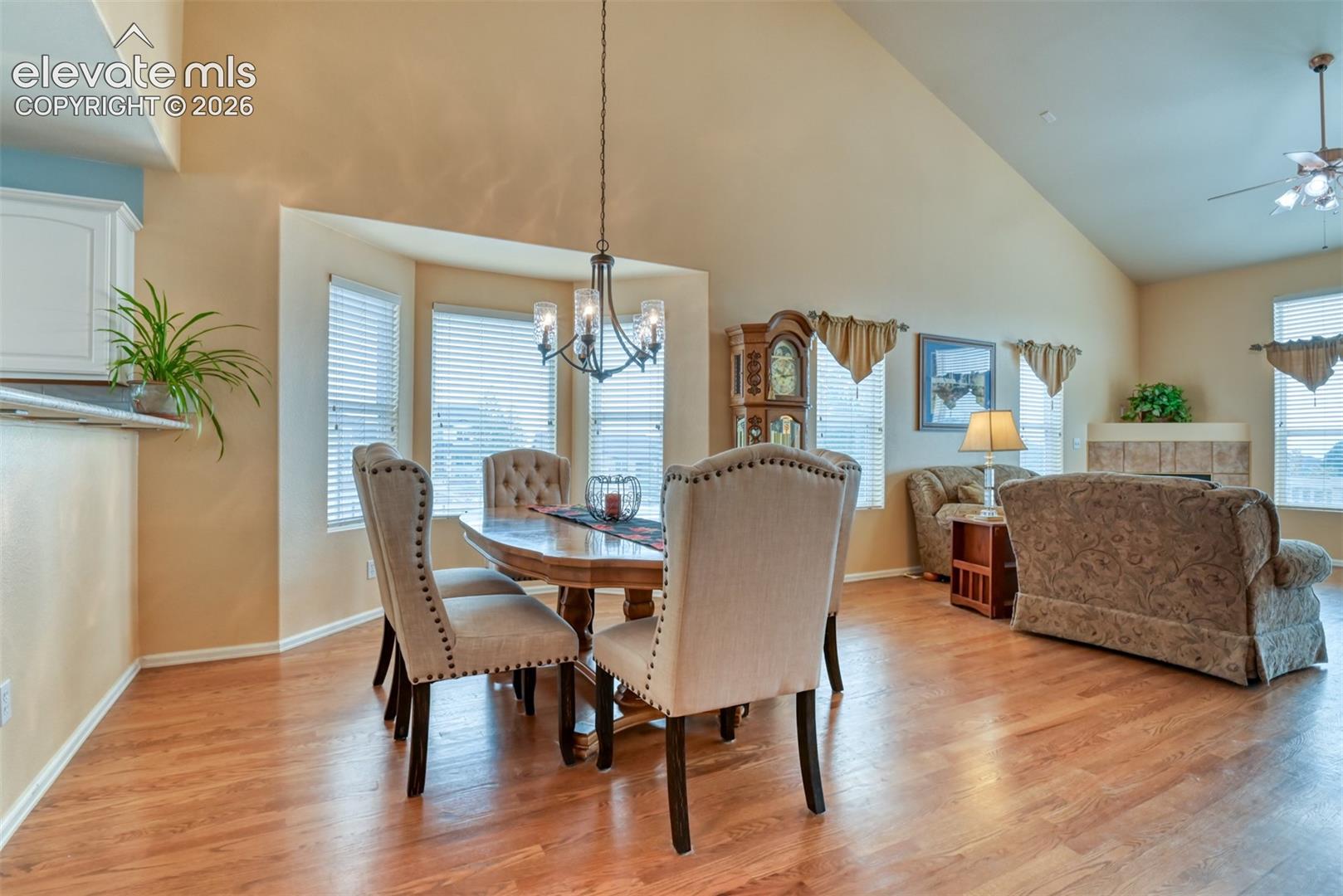 Spacious open-concept interior with vaulted ceilings, hardwood flooring, a bay window