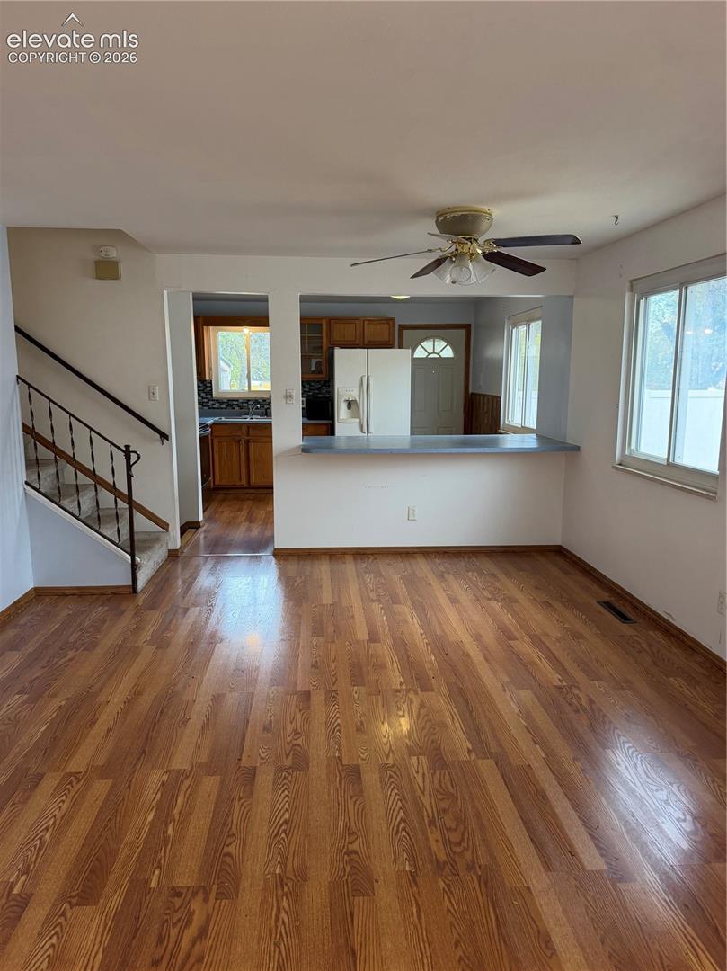 Living area featuring wood-finish flooring, a ceiling fan, and a pass-through breakfast bar
