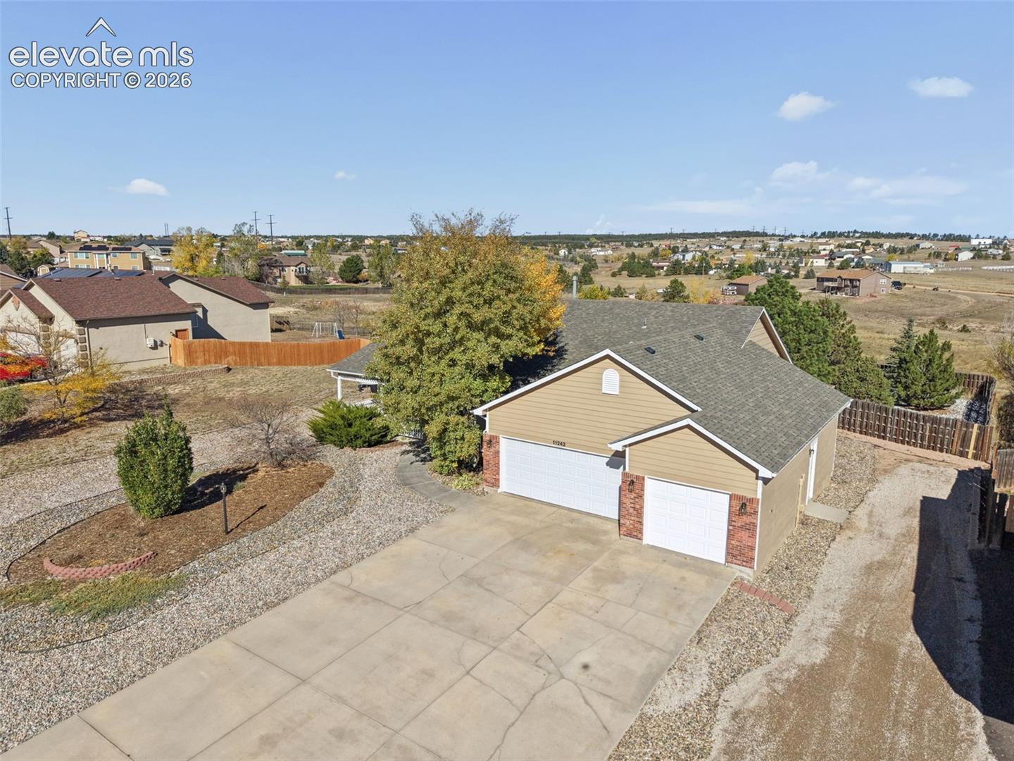 Single-story residence featuring horizontal siding, brick masonry accents, an attached two-car garage, and concrete driveway on a landscaped lot