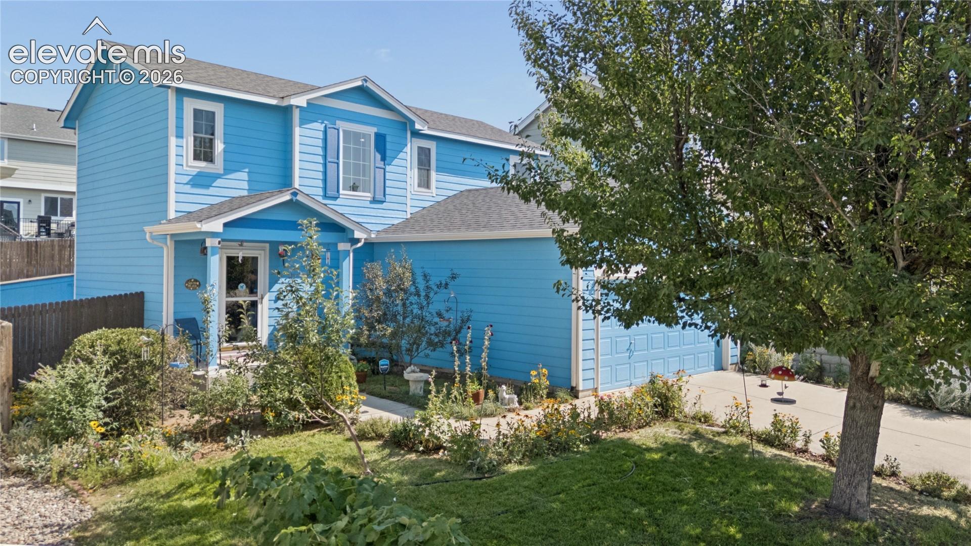 Two-story residence with a covered entryway, attached two-car garage, and a manicured front lawn