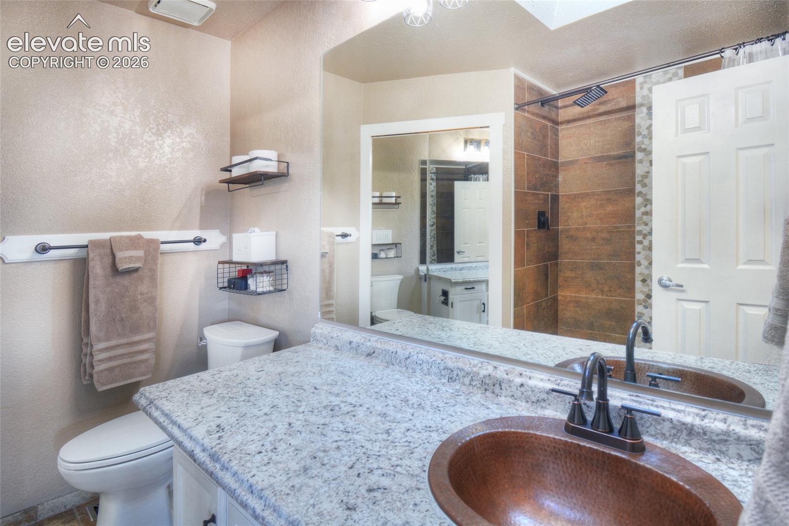 Primary bathroom has a beautiful updated tiled shower, copper sink and walk in closet.
