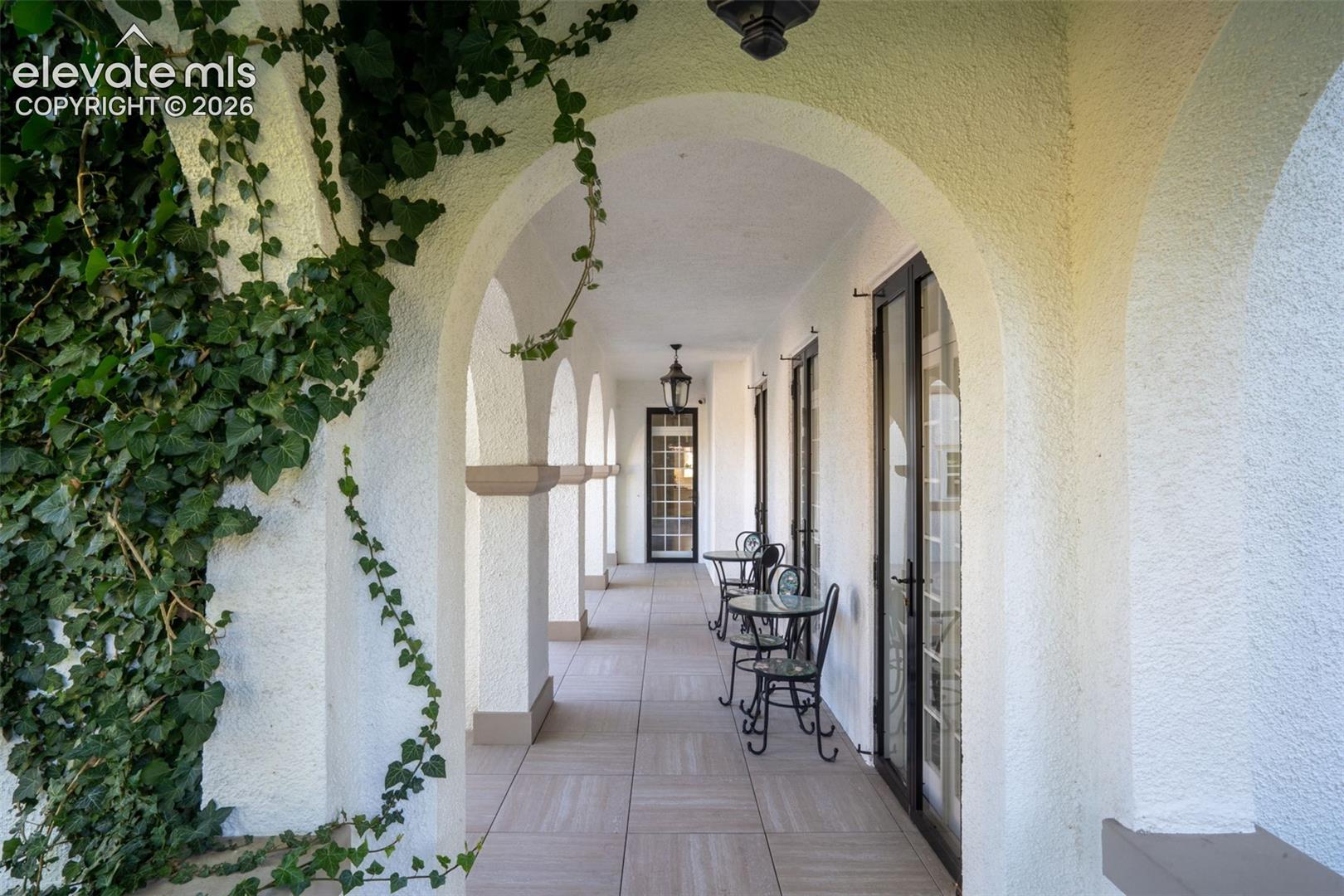 Covered loggia featuring a series of structural arches, stone-finish tile flooring, and integrated wall-mounted lighting