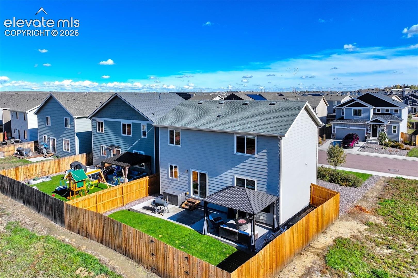 Fenced backyard featuring a concrete patio, metal-roofed gazebo, and lawn area