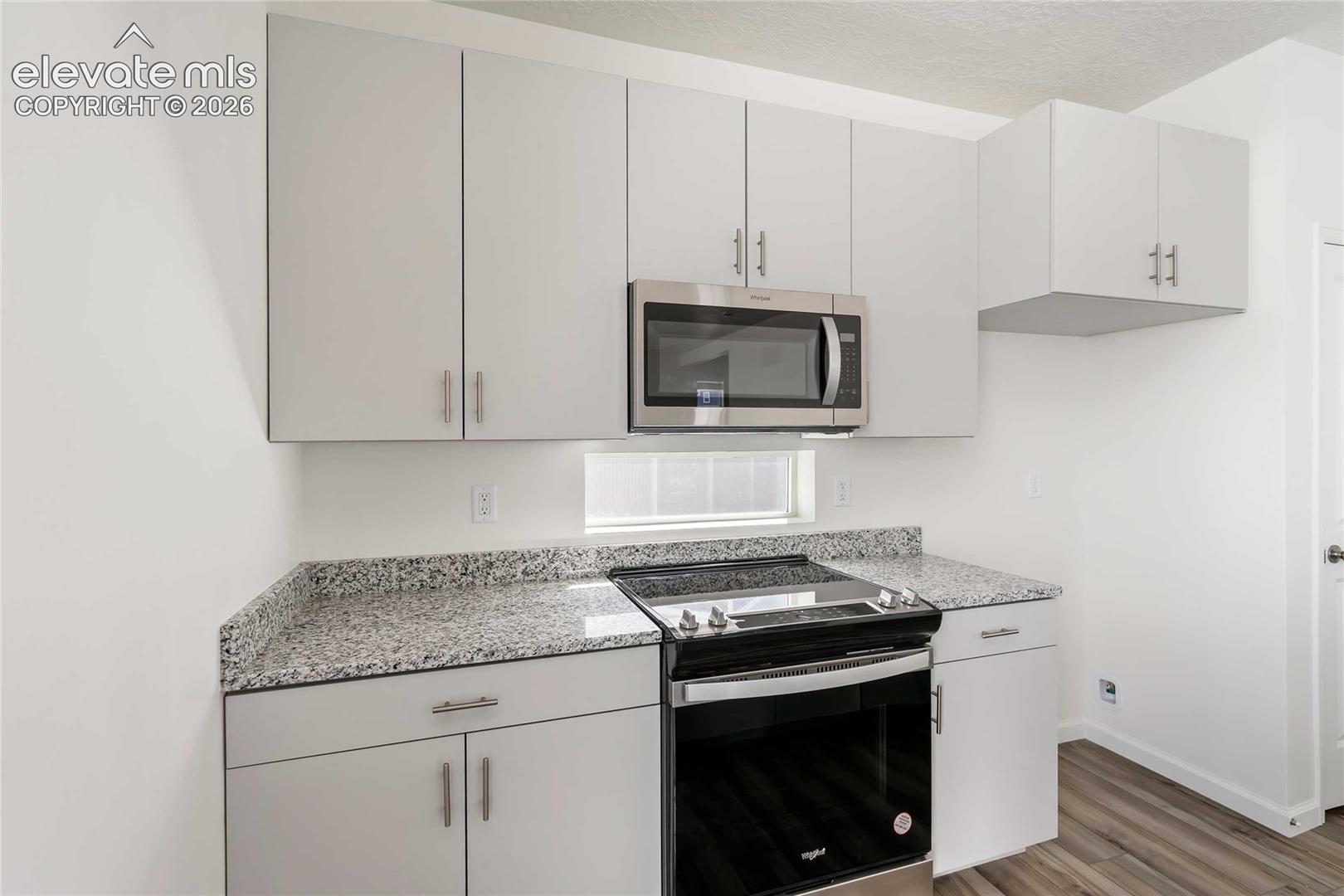 Light gray cabinetry, speckled countertops, stainless steel microwave, and an electric range
*photos of a model home*