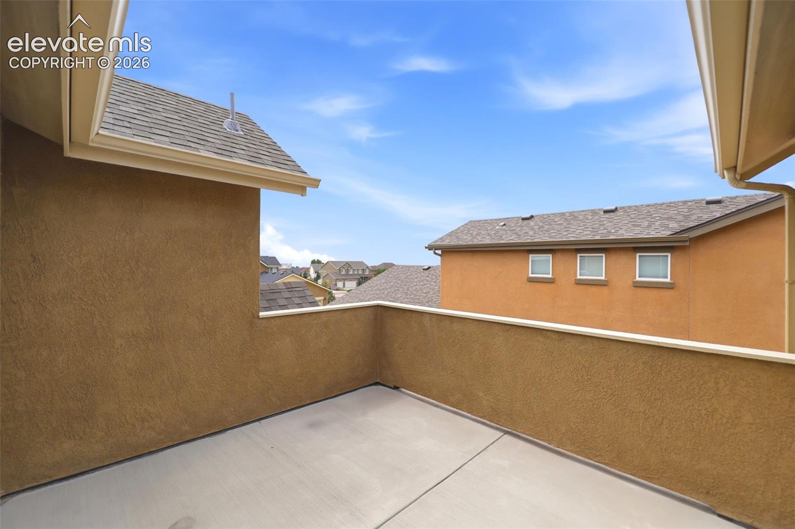Exterior balcony with stucco walls and concrete flooring