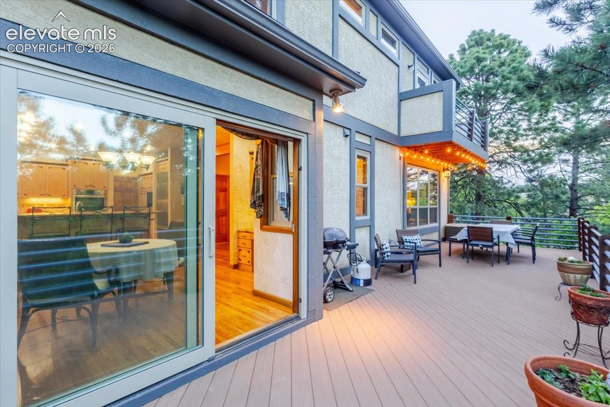 Expansive exterior deck featuring composite decking, modern cable railings, and a balcony above