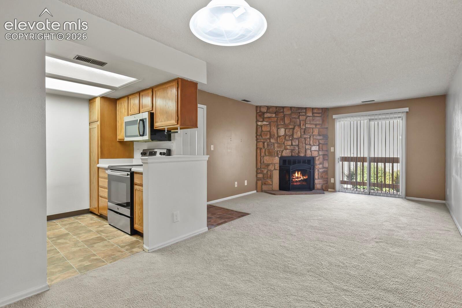 View from the Dining Area looking into the kitchen.  Showing the Stainless Steel freestanding Stainless Steel GE oven with smooth glass range top, GE Stainless Steel  Microwave oven.  Lots of wood cabinets