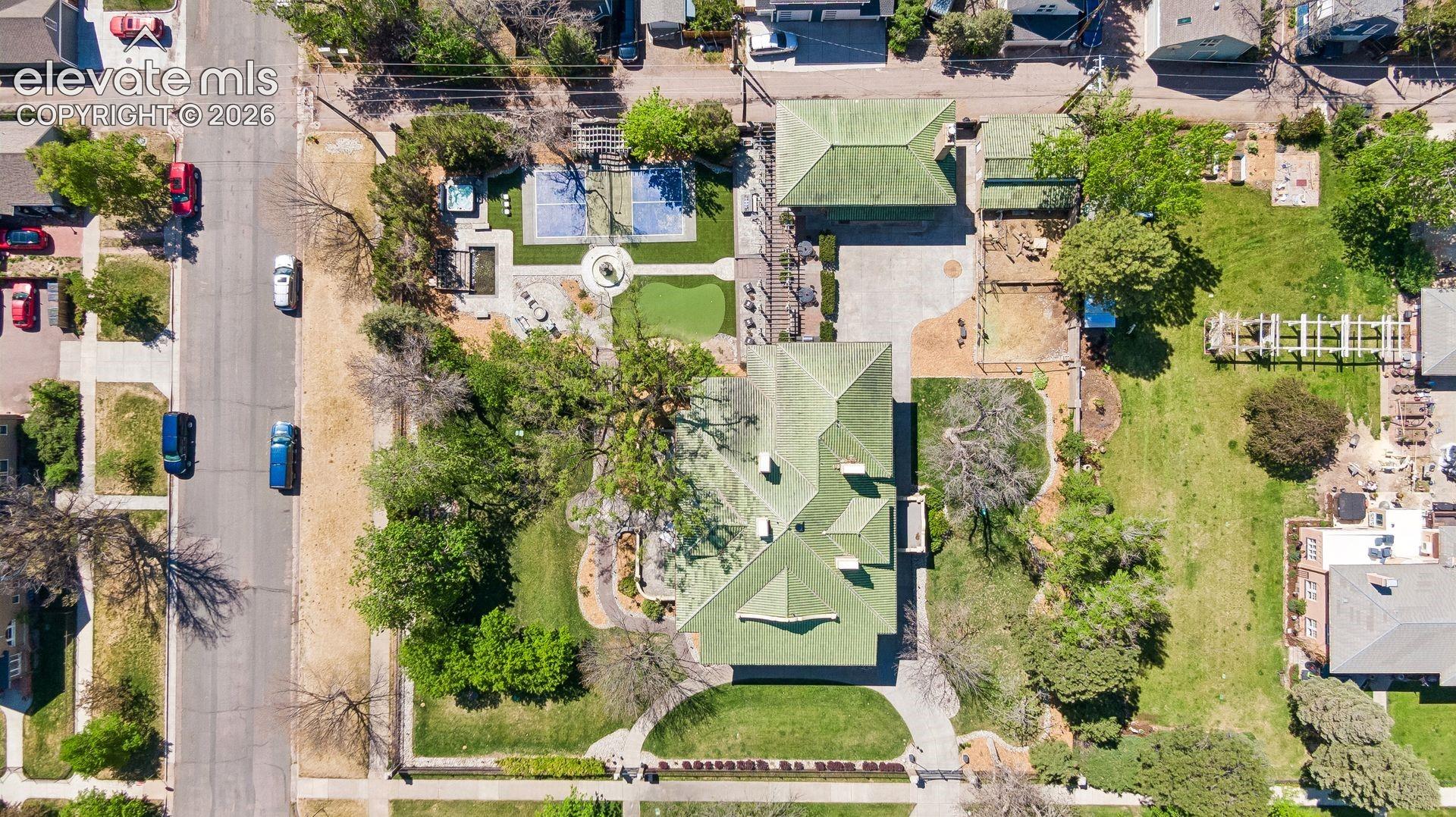 The estate is enclosed by a tall wrought iron fence anchored by stout brick pillars capped with concrete spheres, with electric gate and heated driveway.