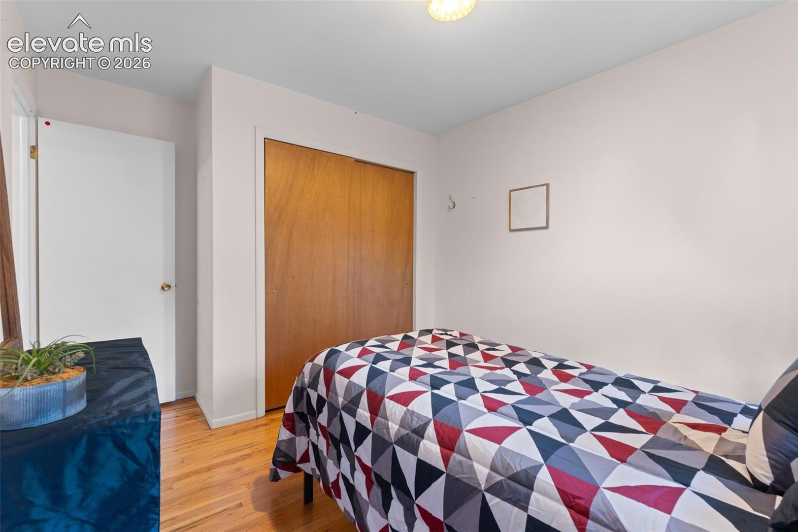 Hardwood-style flooring, white interior door, and a built-in closet with wood-paneled doors