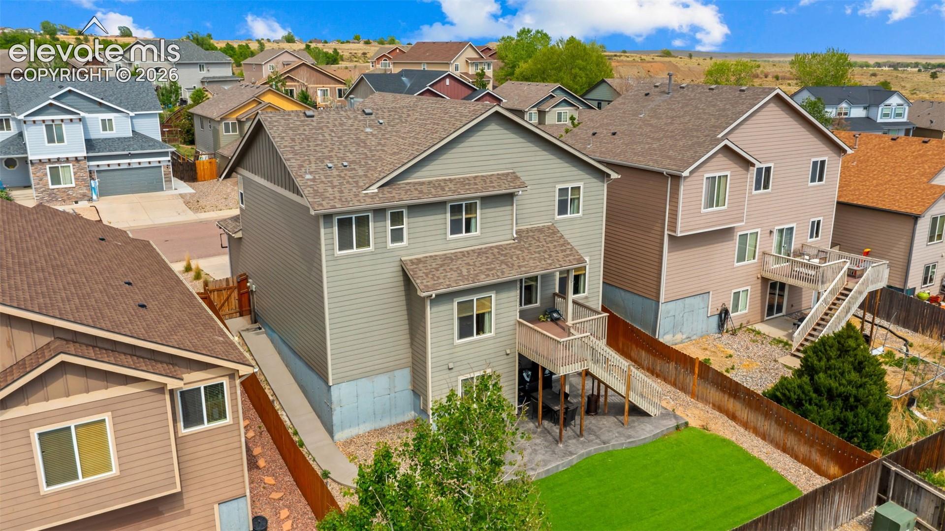 Rear exterior featuring a multi-level deck, lower patio, and fenced yard with artificial turf