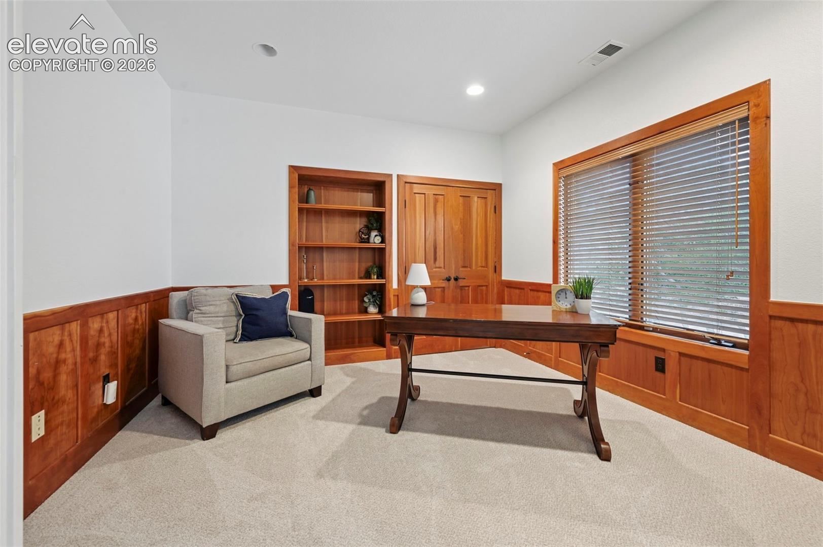 Wood paneling and built-in shelving complement the light-toned carpeting
