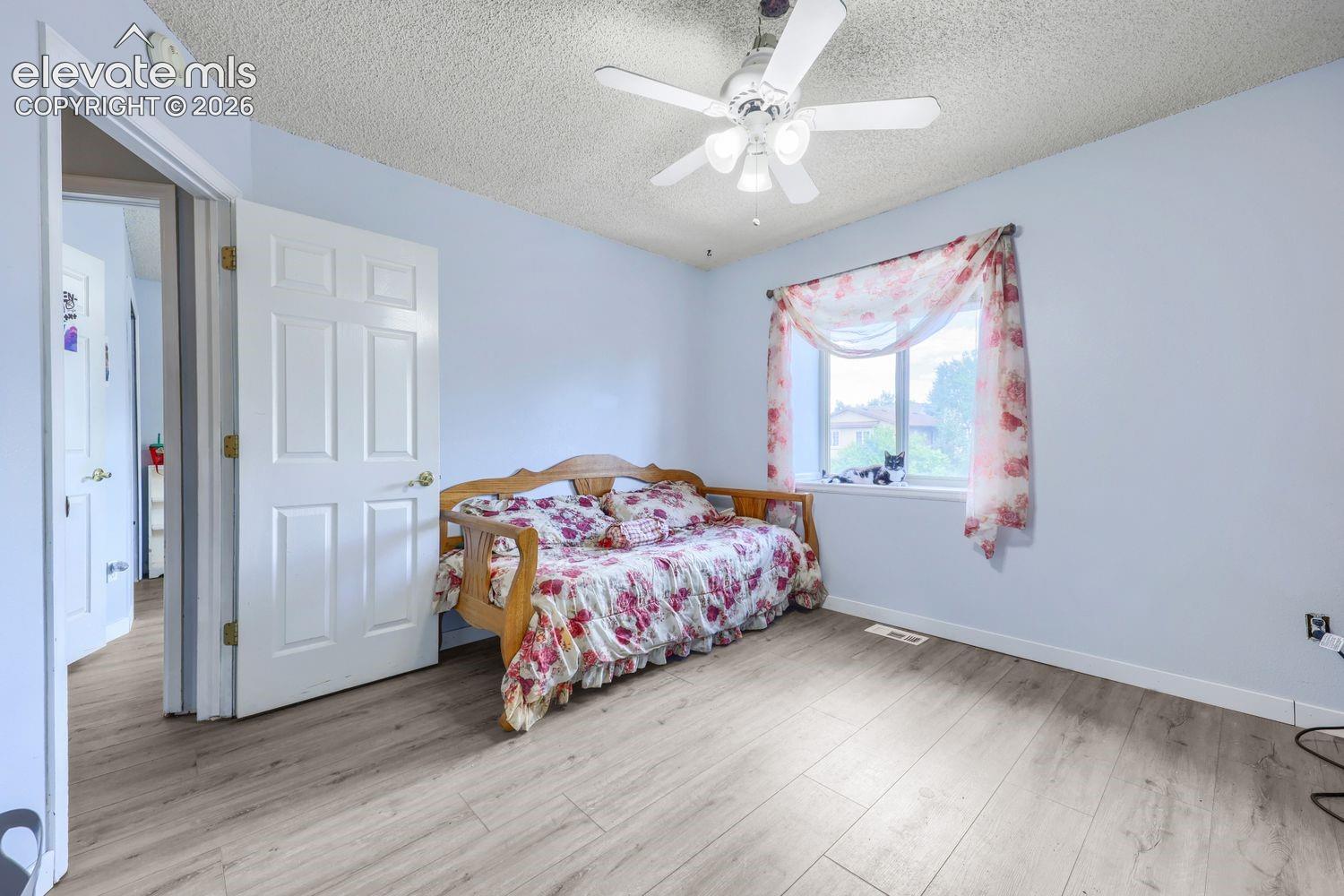 Light-toned wood-finish flooring, white paneled interior doors, and a ceiling fan with integrated lighting