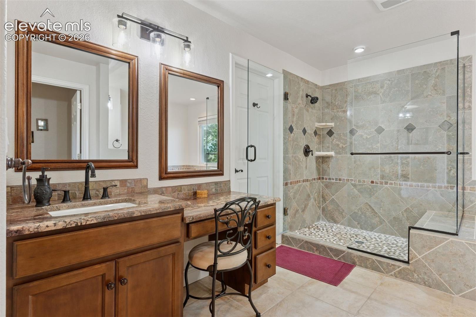 Primary bath with heated floors, multiple vanities, a stall shower w/bench