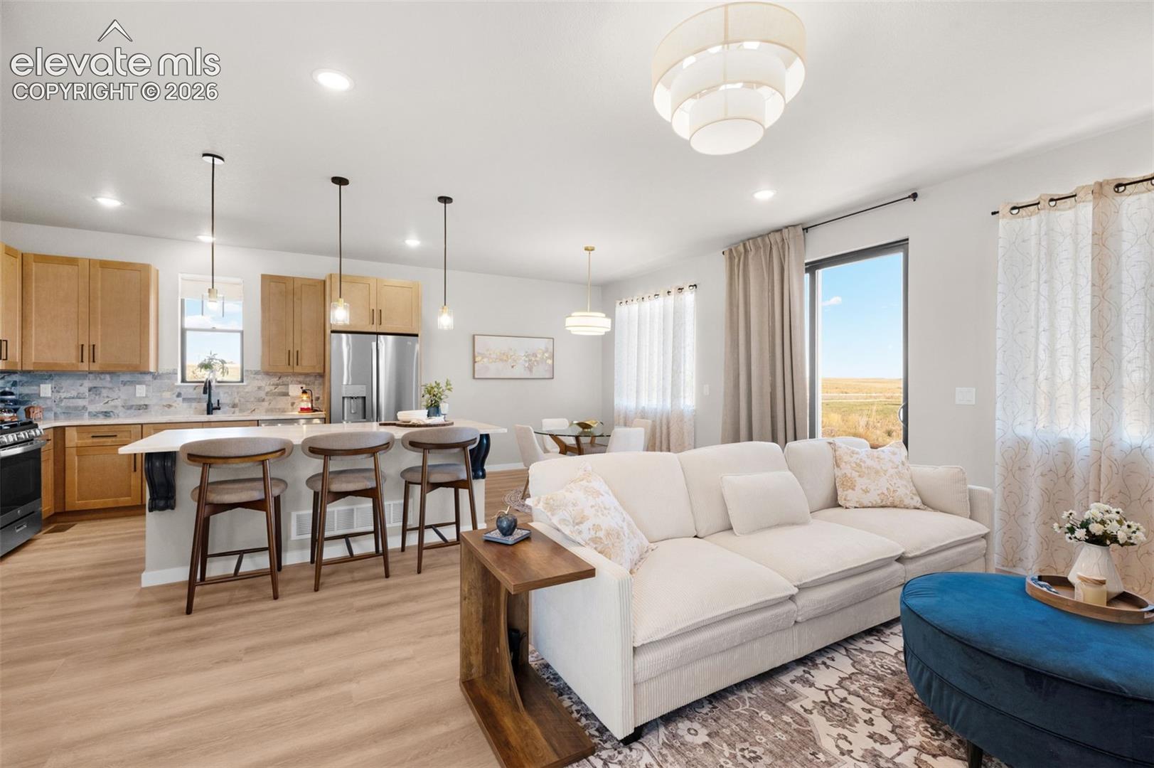 Open concept living area with wood-finish flooring, recessed lighting, and a modern tiered chandelier