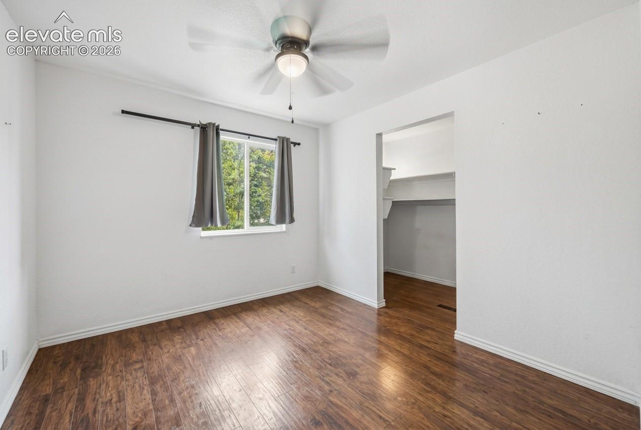Wood-finish flooring, white walls, and a ceiling fan