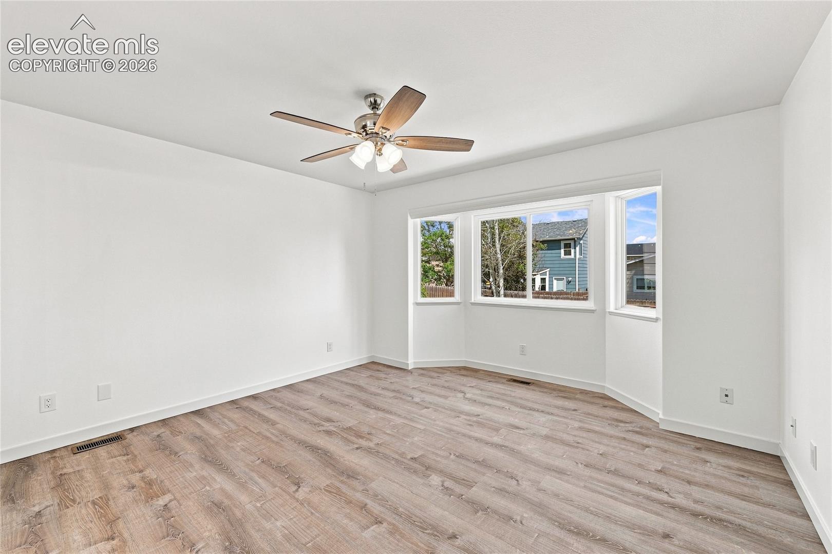 Wood-finish flooring with a ceiling fan and a multi-pane bay window