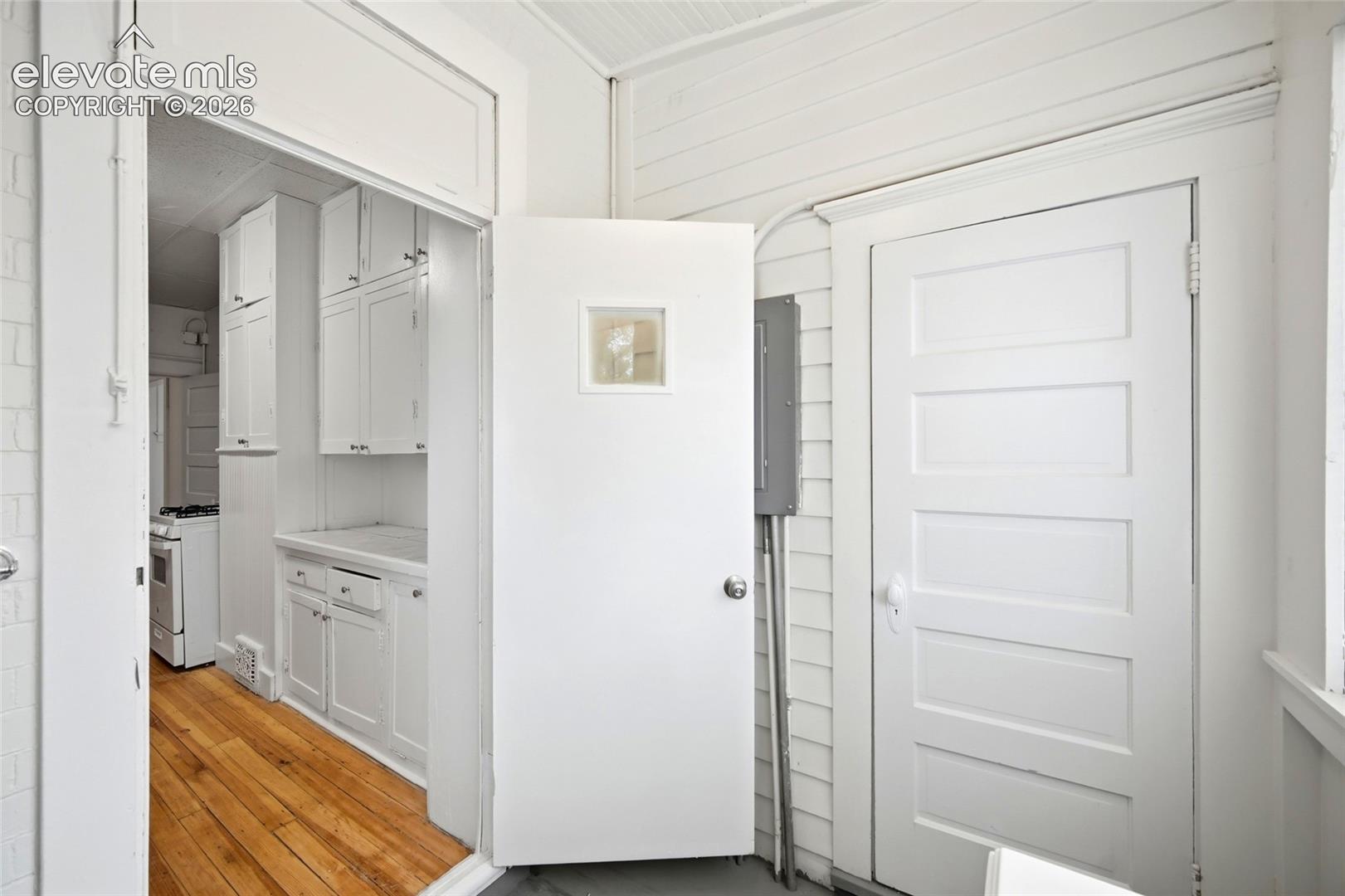Interior featuring horizontal wood wall paneling, a five-panel interior door, and built-in cabinetry with white finish