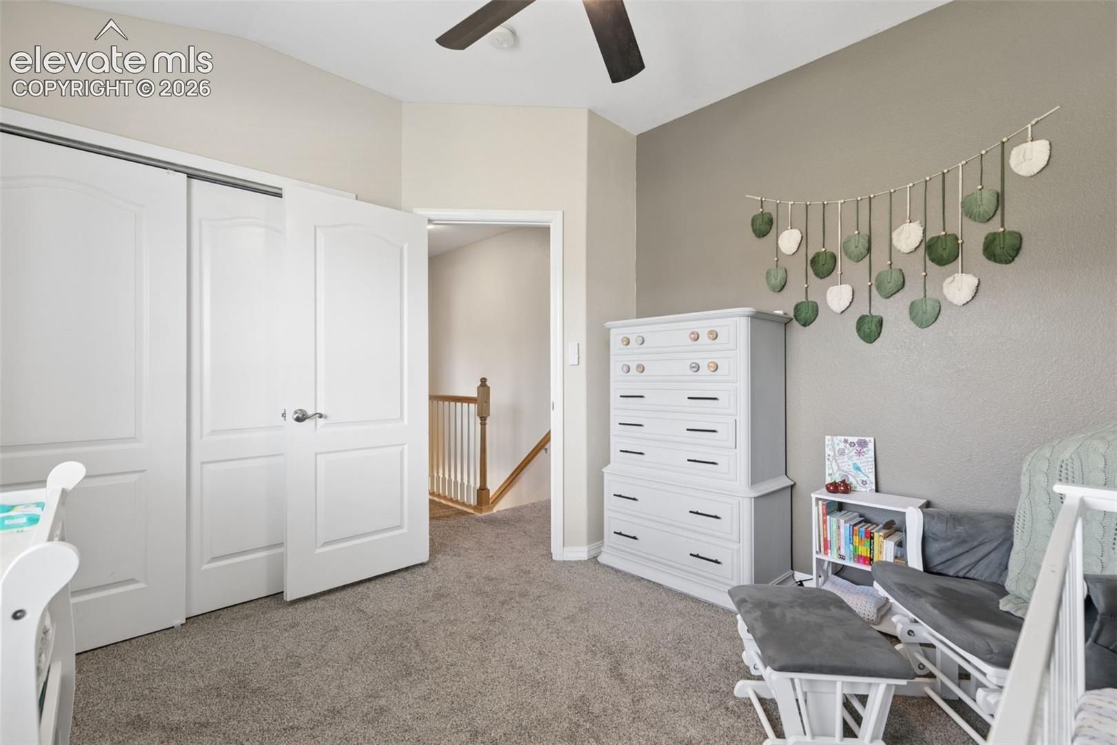 Sliding closet doors, ceiling fan, carpeted flooring, and a neutral color palette