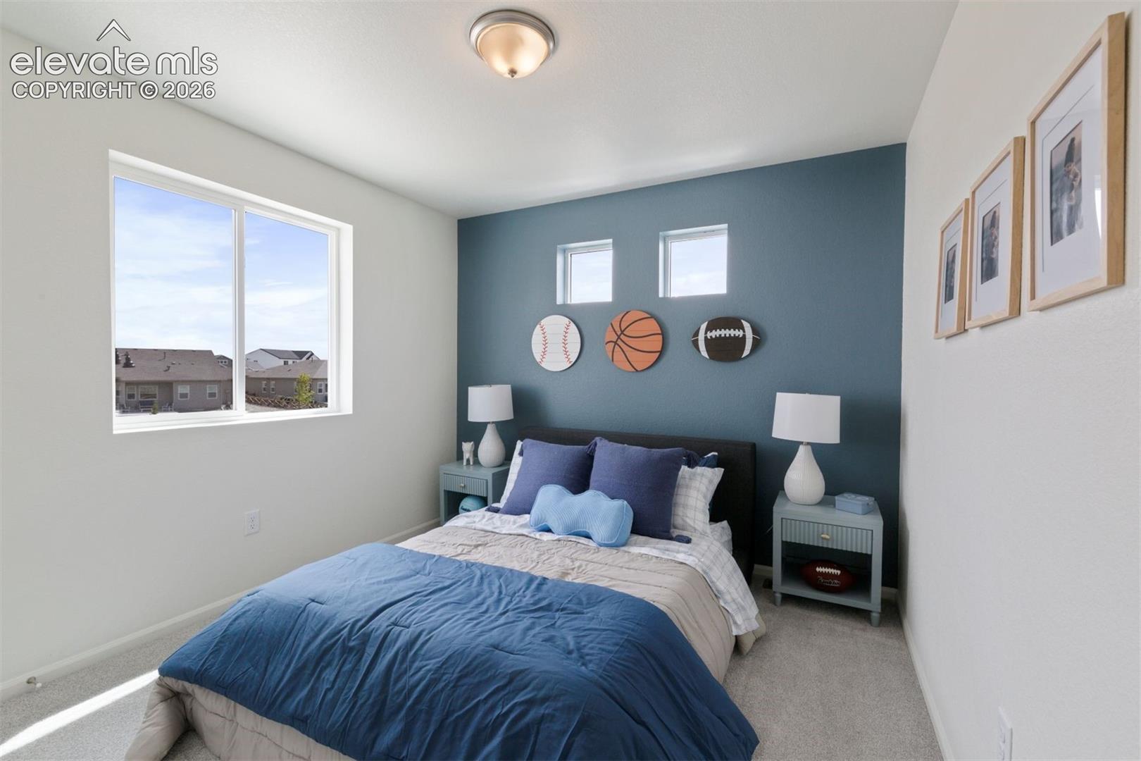 Spacious bedroom featuring light neutral carpeting, a large picture window, a flush mount ceiling light, and a contrasting accent wall
*photos of a model home*