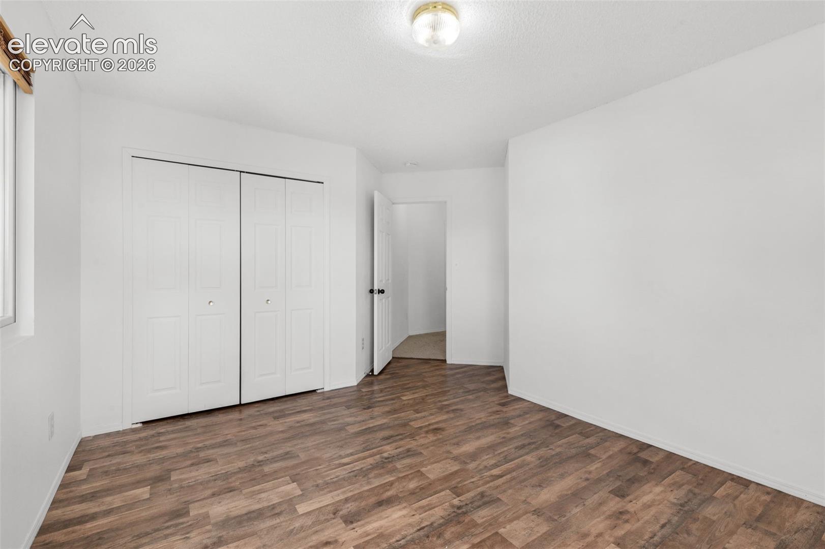 Wood-finish flooring with white walls and bi-fold closet doors