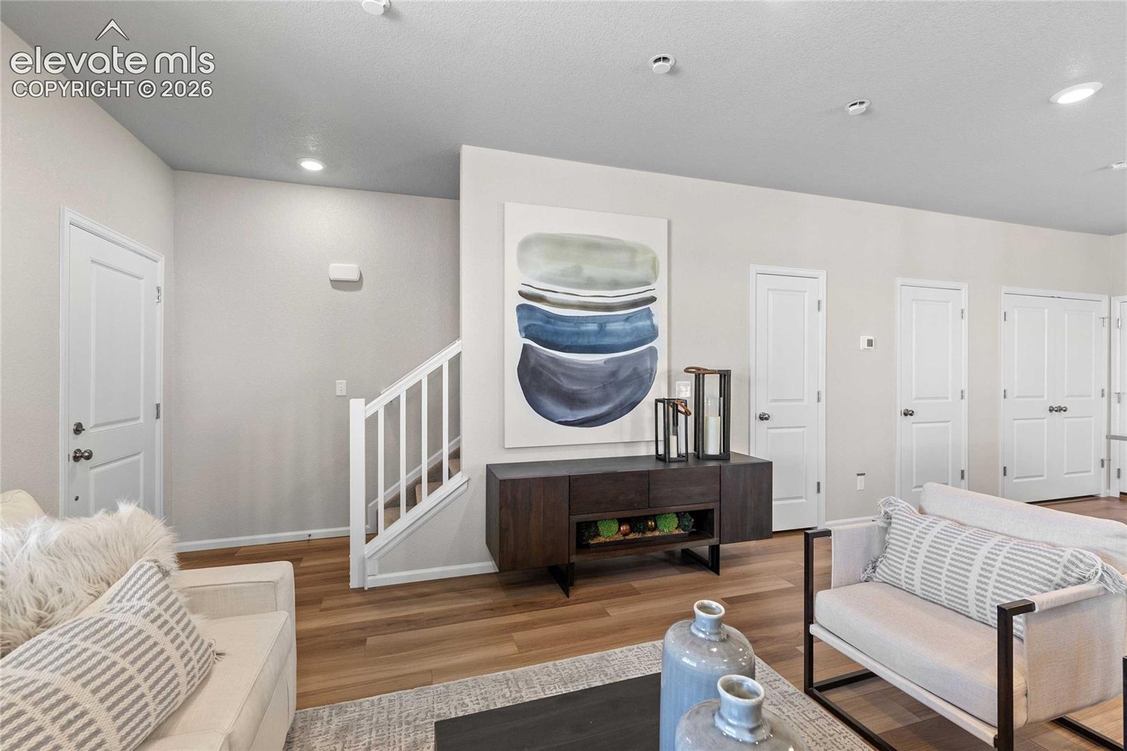 Wood-finish flooring, white paneled doors, recessed lighting, and a white staircase with wood handrails
*photos of a model home*