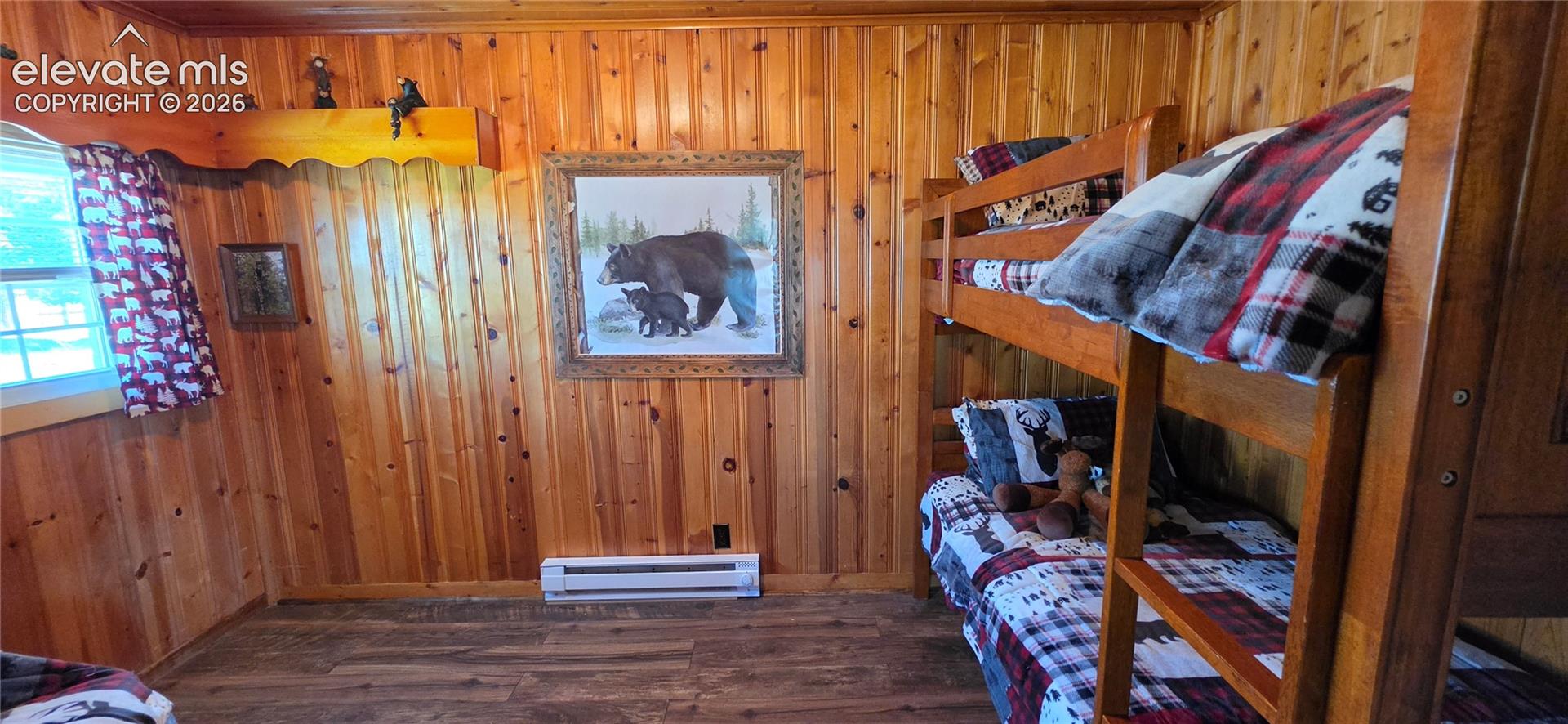 Wood-paneled walls, wood-finish flooring, built-in bunk beds, and a window for natural light