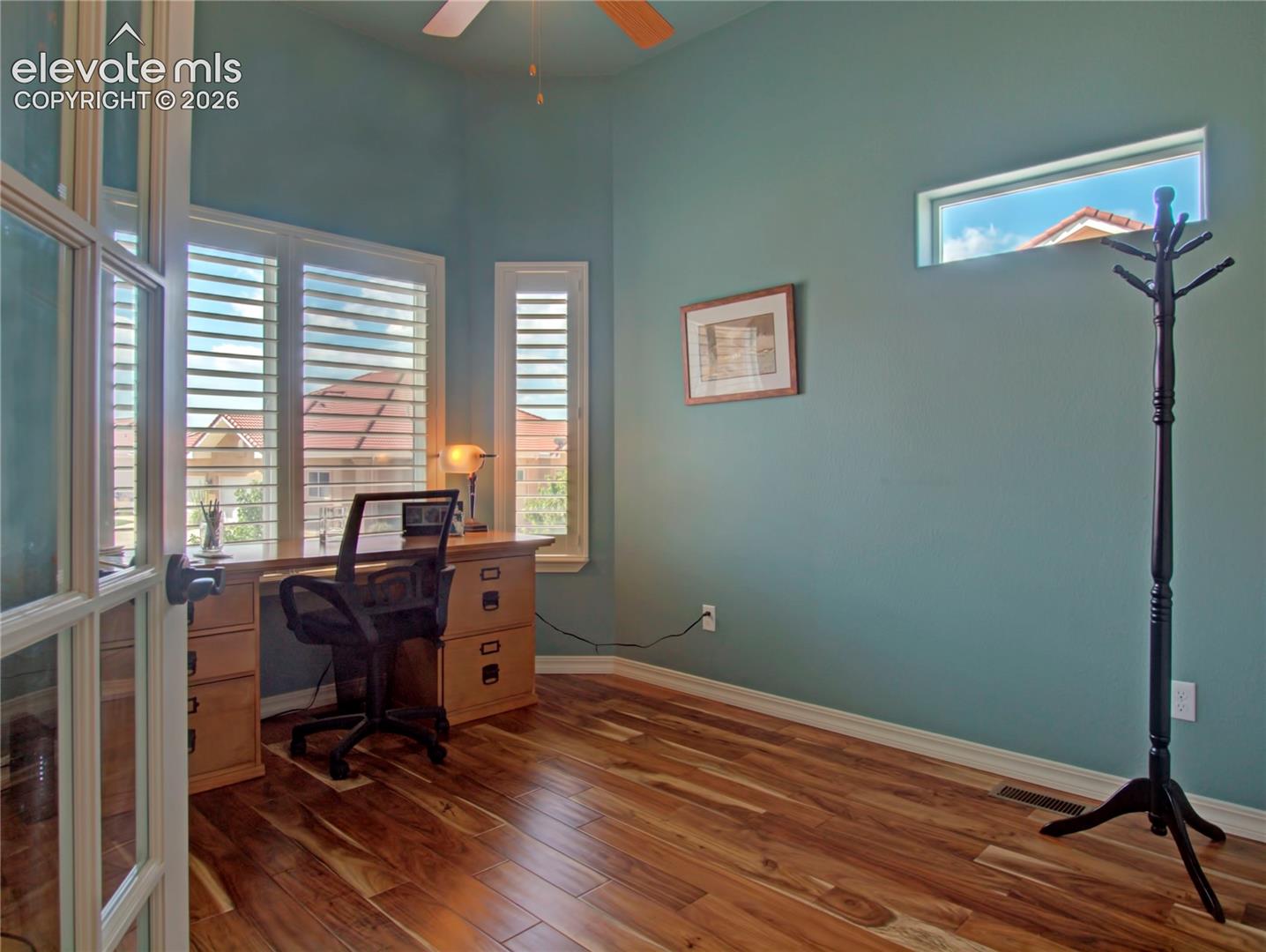Bedroom or office. featuring wood-finish flooring, high ceilings, and a ceiling fan