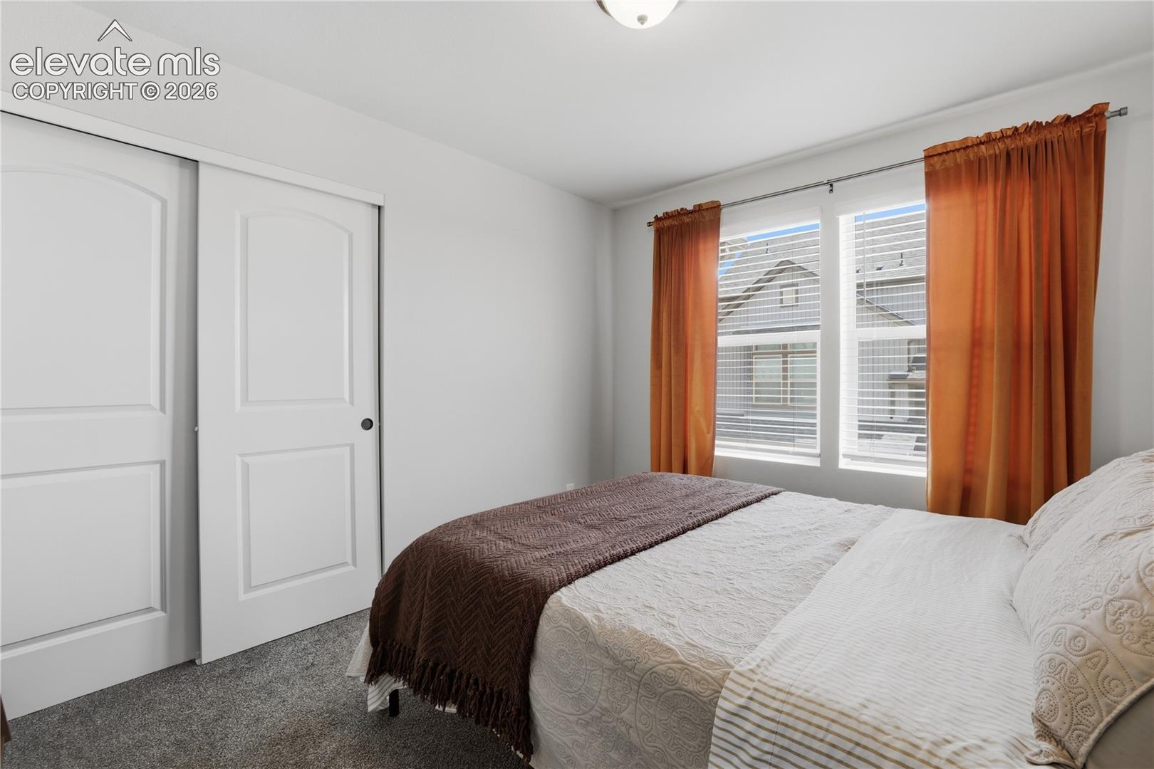 Bedroom featuring carpet flooring, dual pane windows with blinds, and white interior doors