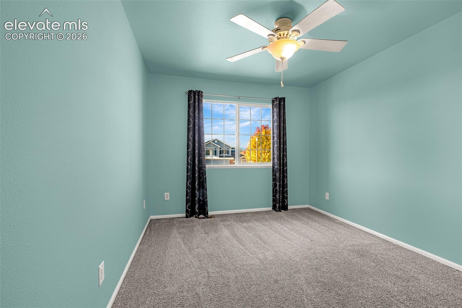 Room featuring wall-to-wall carpeting, a dual-pane window, and a ceiling-mounted light fixture with a fan