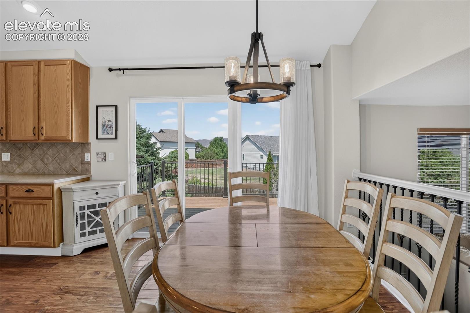 Dining area featuring wood-finish flooring, a contemporary chandelier, and direct access to an outdoor deck through a sliding glass door