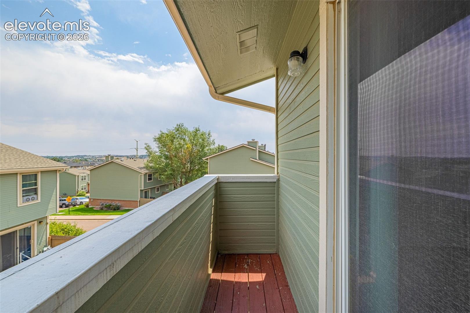 Balcony with horizontal siding, wood-finish flooring, and exterior lighting fixture