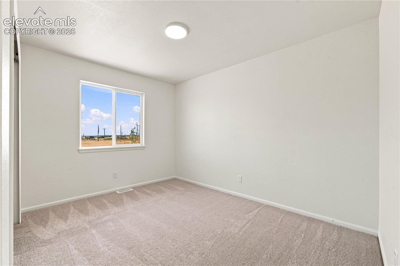 Bright room featuring a double-pane window, neutral carpet, white walls, and a ceiling-mounted light fixture
