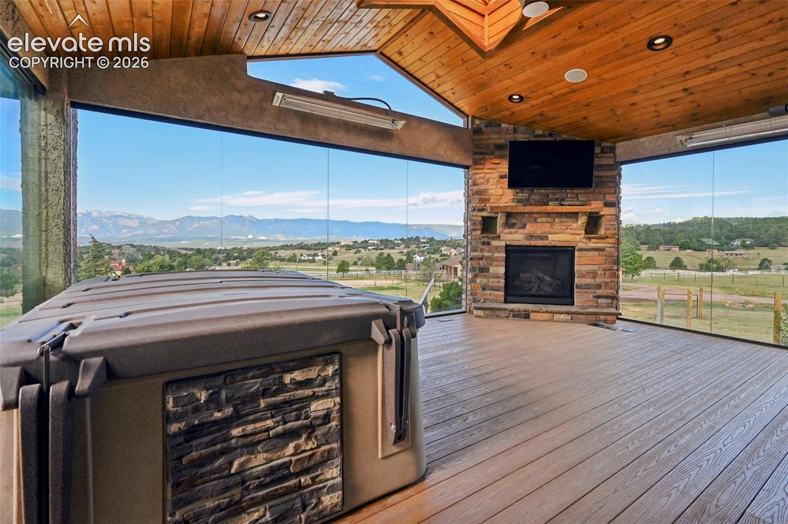 Enclosed patio featuring a stone fireplace, natural wood ceiling and recessed lighting