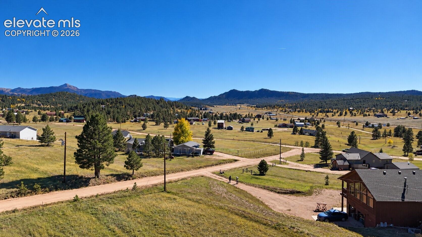 Aerial perspective showcasing expansive acreage, natural mountainous terrain, mature coniferous trees, and unpaved roads