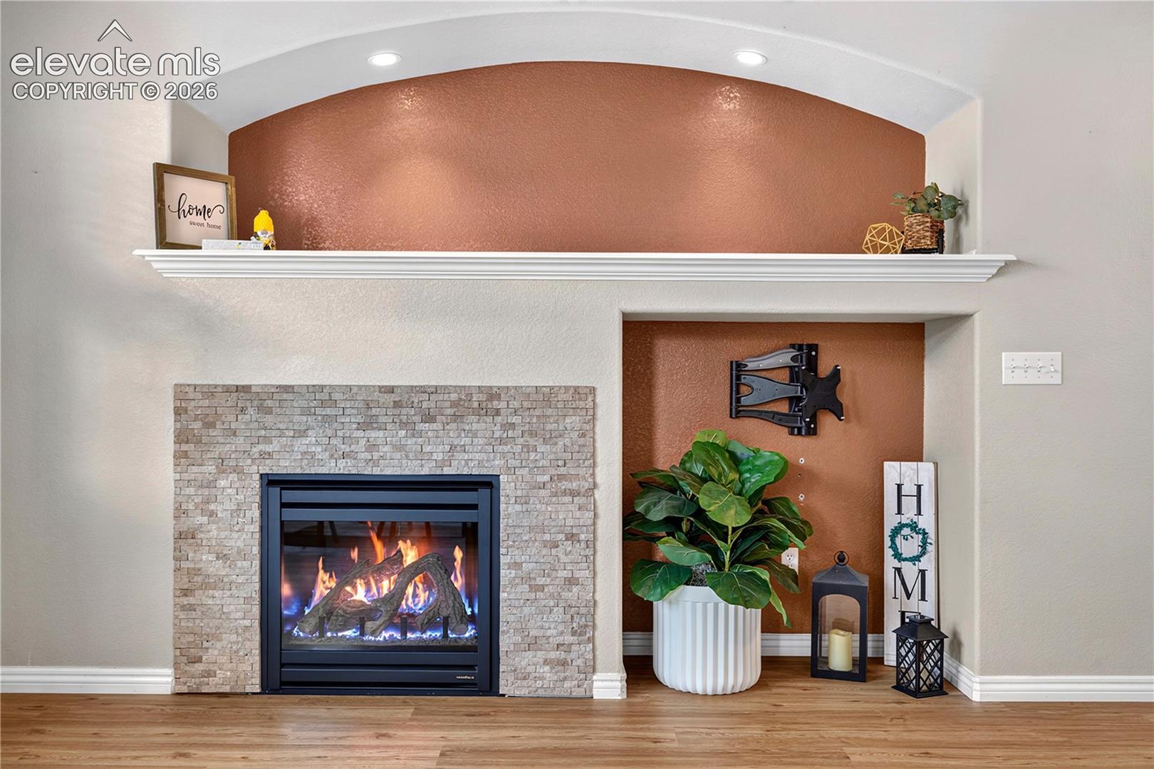 Fireplace with stacked stone surround, integrated mantel, recessed arched display niche, tv mount.