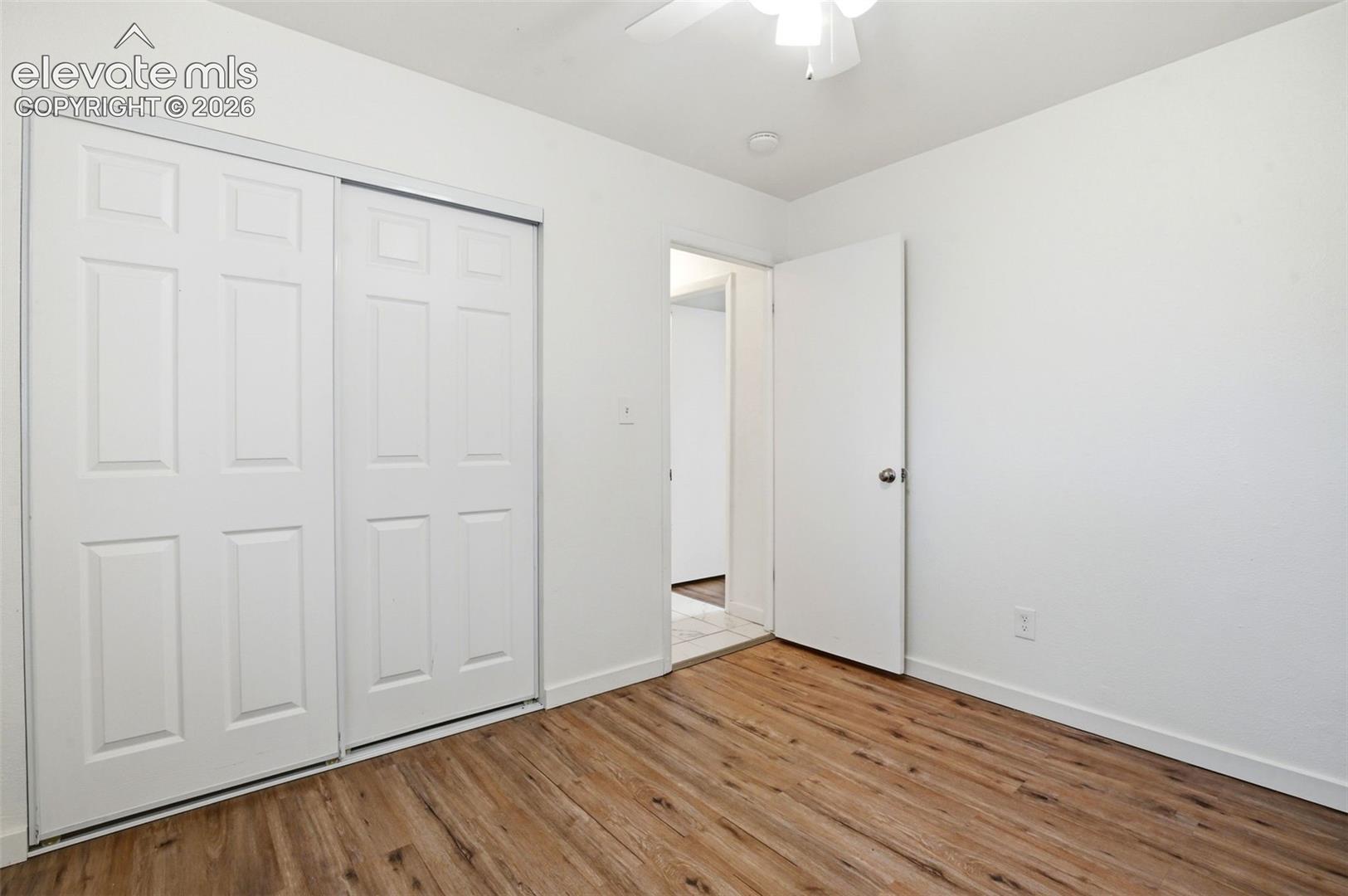 Spacious Office, could be a Bedroom featuring warm wood-finish flooring, dual sliding closet doors with panel detailing, and an additional entry door