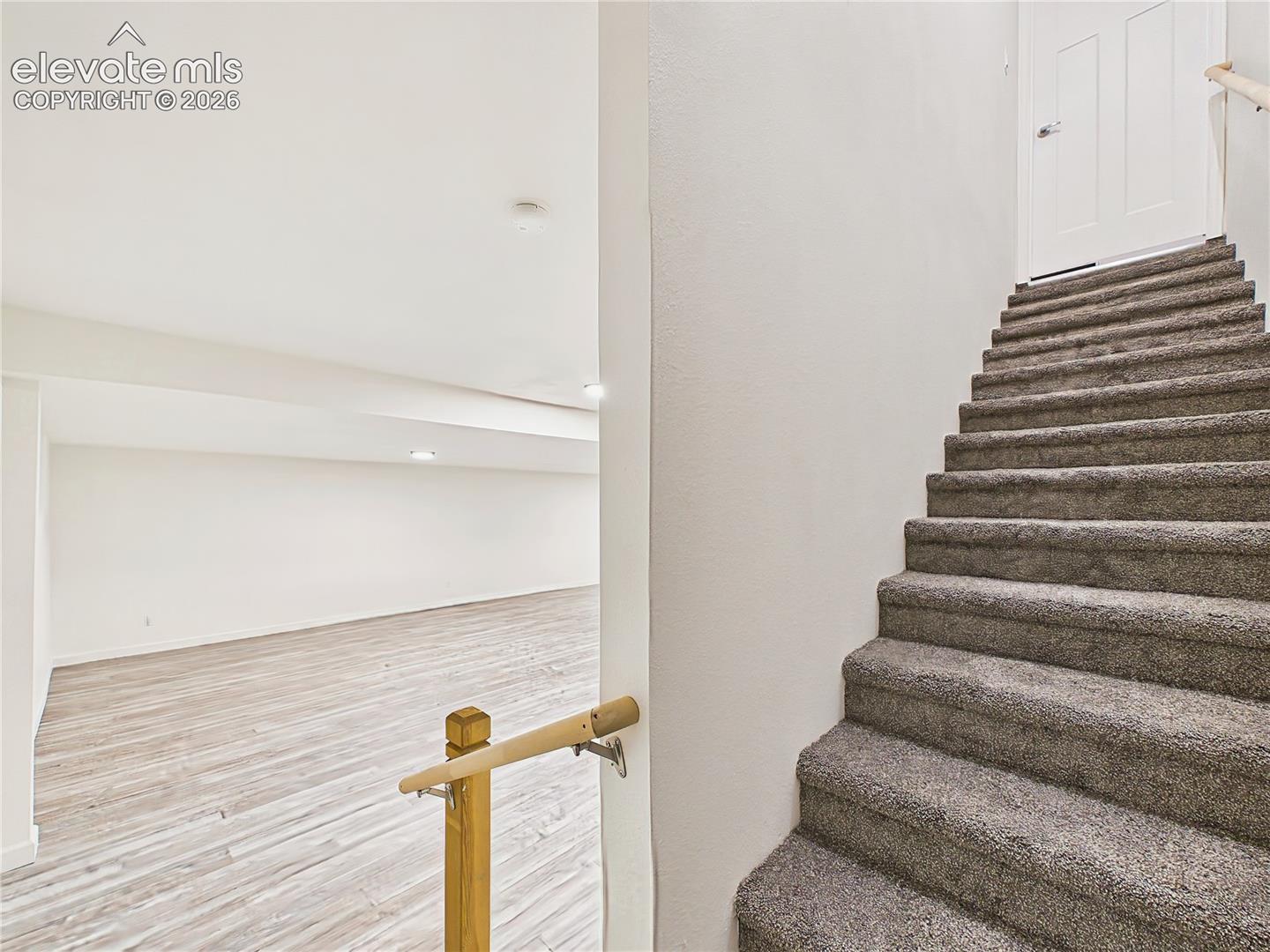Carpeted stairs lead to the finished walk-out basement, opening to an expansive recreation and family-room area with durable flooring and recessed lighting.