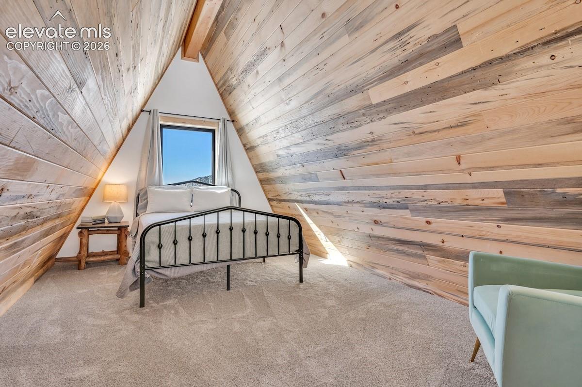 A-frame interior featuring vaulted ceilings with exposed wood-plank paneling, neutral carpeting, and a centered window
