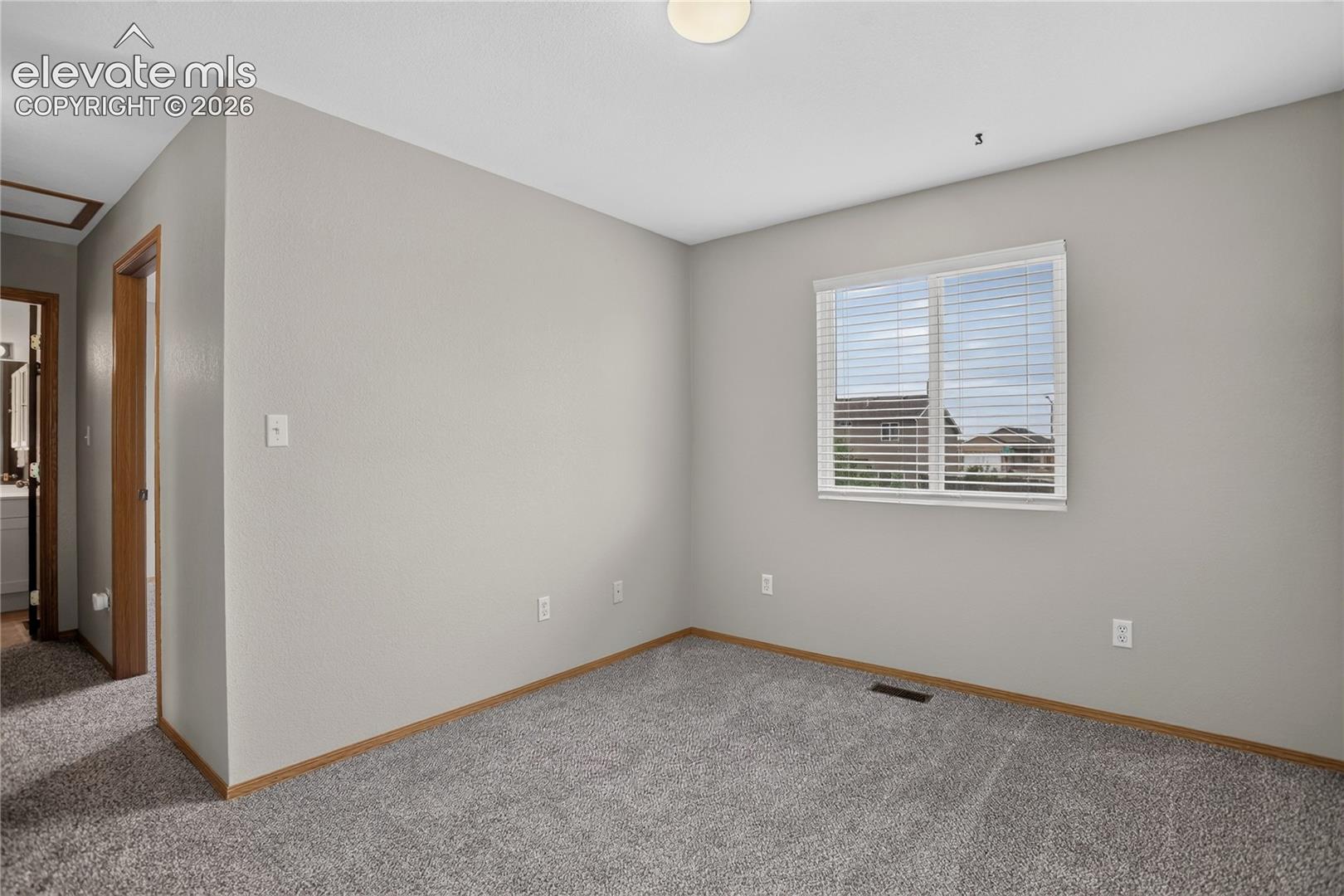 Carpeted room with a window, white blinds, and light-colored walls
