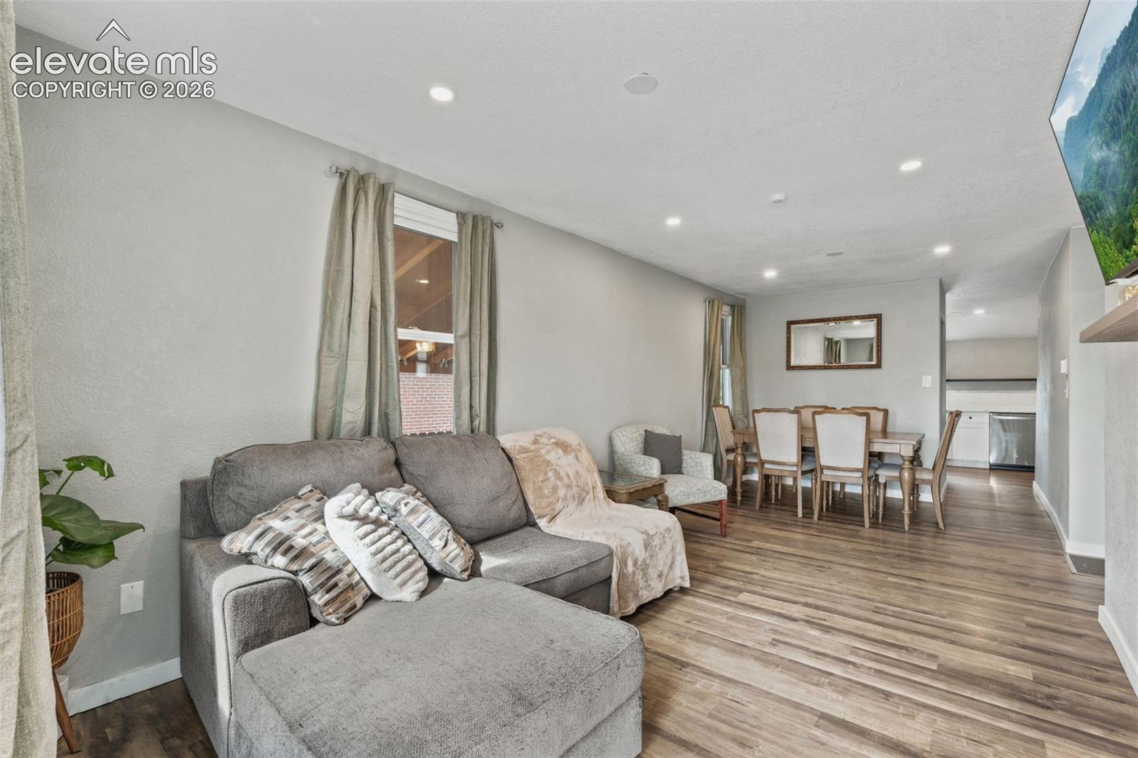 Open-concept living space featuring recessed lighting, wood-finish flooring, and a neutral color palette