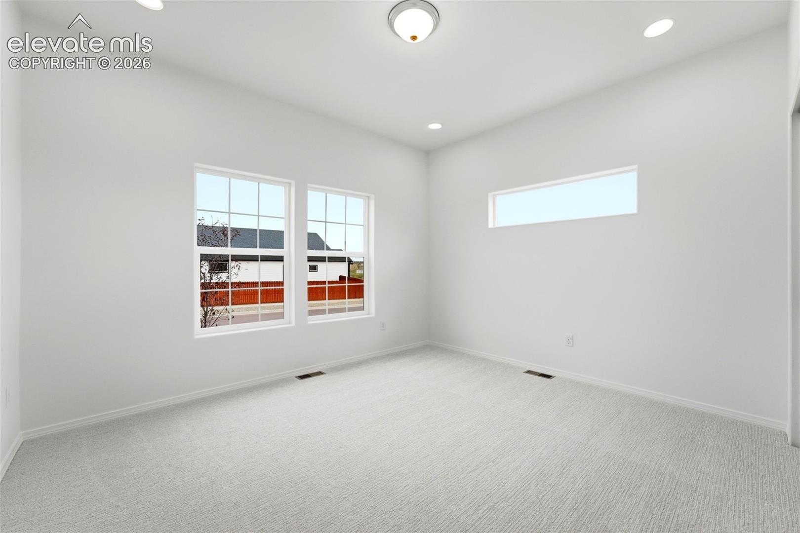 Interior room featuring vaulted ceilings, neutral wall-to-wall carpeting, recessed lighting, double-hung windows, and a high-set transom window